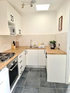 una cocina blanca con armarios blancos y fregadero en Sunlight Cottage en Ciudad del Cabo