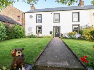 a house with a teddy bear statue in the yard at Glenridding Cottage in Warcop