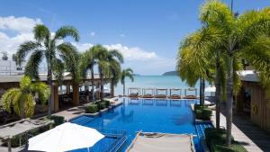 an infinity pool with palm trees and the ocean at Selina Serenity Rawai Phuket in Rawai Beach