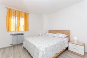 a white bedroom with a bed and a window at Apartments Marinko in Makarska