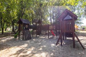 einen Spielplatz in einem Park mit Bäumen im Hintergrund in der Unterkunft Angolkert Panzió in Téglás