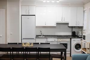 a kitchen with white cabinets and a table with chairs at Pensión Txoko Goxoa in Hondarribia