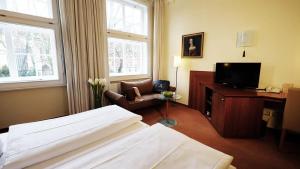 Schlafzimmer mit einem Bett, einem Schreibtisch und einem TV in der Unterkunft Hotel zur Fürstabtei in Herford