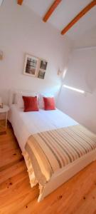 een wit bed met rode kussens in een kamer bij Fabulous apartment by Douro River in Porto