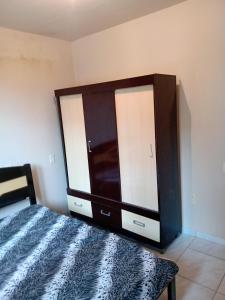 1 dormitorio con 1 cama y armario de madera en Casa a 40 metros da praia en Governador Celso Ramos