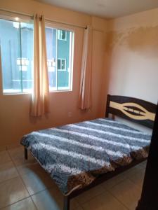 - une chambre avec un lit et 2 fenêtres dans l'établissement Casa a 40 metros da praia, à Governador Celso Ramos