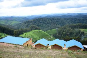 um grupo de casas numa colina com montanhas ao fundo em NYUNGWE VILLAGE em Kitabi