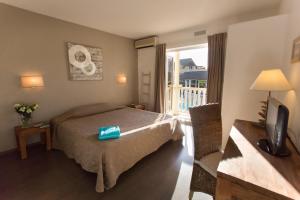 um quarto de hotel com uma cama e uma varanda em Hôtel Exsel Ermitage em Saint-Gilles-les Bains