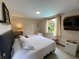 ein Schlafzimmer mit einem großen weißen Bett und einem Fenster in der Unterkunft Pousada Nova Gironda in Paty do Alferes