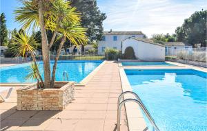a swimming pool with a palm tree next to a house at 1 Bedroom Stunning Home In Dolus-dolron in Dolus d'Oléron