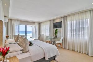 a bedroom with a large bed with a view of the ocean at Hermanus Beachfront Lodge - Solar Power in Hermanus