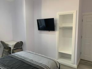 um quarto com uma cama e uma televisão na parede em Ibrox Argyll Sky Suite em Glasgow