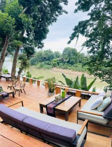 a patio with couches and tables and a view of a river at Moonlight Champa Riverview in Luang Prabang