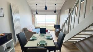 salon ze stołem i krzesłami oraz schodami w obiekcie Appartement vue mer, Brigantine w mieście Fort-Mahon-Plage