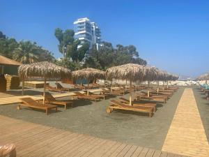 a row of chairs and straw umbrellas on a beach at Samson Sea Breeze, 3bed sleeps 6, free WiFi in Limassol