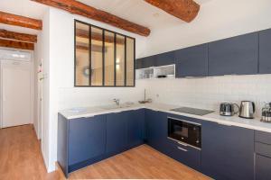 a large kitchen with blue cabinets and a window at Very Nice 58m Close To The Old Port in Marseille