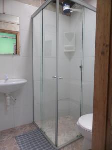 y baño con ducha de cristal y aseo. en Casinhas Vila Bonita Azul, en Baía Formosa