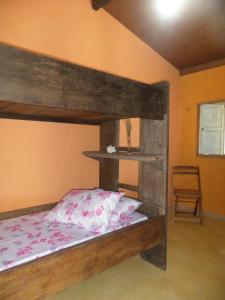 1 dormitorio con litera de madera y silla en Casinhas Vila Bonita Azul, en Baía Formosa