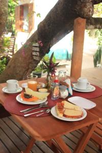 una mesa de madera con platos de comida. en Pousada Aroeira, en Caraíva