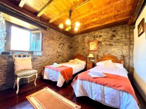 1 dormitorio con 2 camas y pared de piedra en Casa con 2 dormitorios, chimenea, jardin y vista a la montaña, en Campomanes