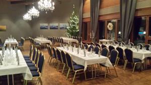un salón de banquetes con mesas y sillas blancas y lámparas de araña en Hotelli Viikinhovi en Keuruu