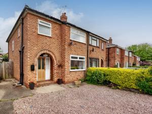 una casa de ladrillo con puerta amarilla y ventanas en The Hawthorns, en Chester