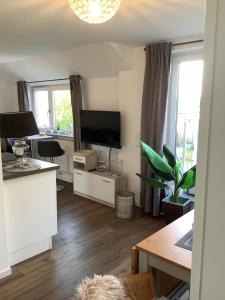 a living room with a flat screen tv and a desk at Residenz am Trammer See in Plön