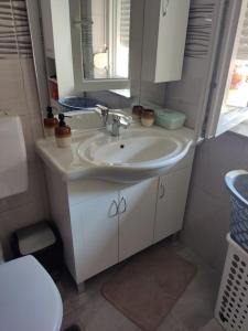 La salle de bains est pourvue d'un lavabo, d'un miroir et de toilettes. dans l'établissement Apartman David-Dražice, à Dražice
