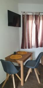 mesa de madera con 2 sillas azules y TV en Tiny House Nike, en Tettnang
