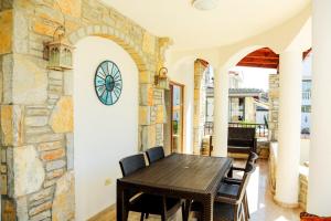 Stunning 4-Bedrooms Villa in Dalyan Turkey في داليان: غرفة طعام بجدار حجري وطاولة وكراسي خشبية