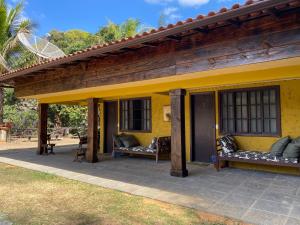 a yellow house with benches on a patio at Pousada Nova Gironda in Paty do Alferes