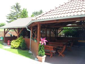a wooden pavilion with wooden benches and a pink flower at Guesthouse Zuzana in Špačince