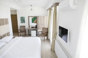 a white bedroom with a bed and a tv at Sun Bella Konaklama in Kırklareli