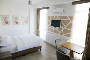 a bedroom with a bed and a desk and a tv at Sun Bella Konaklama in Kırklareli