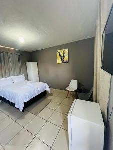 a bedroom with a bed and a chair in it at Tshukudu Guesthouse in Soweto