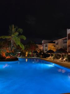 a large blue swimming pool with palm trees at night at Karibo Punta Cana in Punta Cana