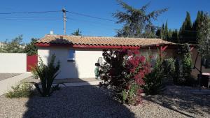 una pequeña casa blanca con flores delante en Tranquillité B&B, en Cuxac-dʼAude