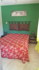 1 dormitorio con cama roja y pared verde en Tranquillité B&B, en Cuxac-dʼAude