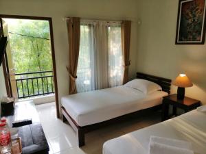 a bedroom with two beds and a large window at Puri Pangeran Hotel in Yogyakarta