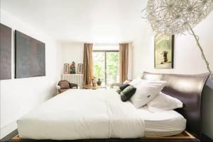 ein Schlafzimmer mit einem großen Bett mit weißen Laken und Kissen in der Unterkunft Villa Alesia in Paris