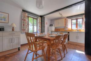 a kitchen with a wooden dining table and chairs at Vine Cottage in Musbury