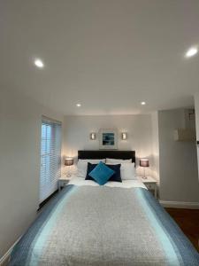 een witte slaapkamer met een groot bed met blauwe kussens bij Fuchsia Cottage in Flushing