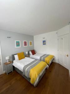 two beds in a bedroom with white walls and wood floors at Fuchsia Cottage in Flushing