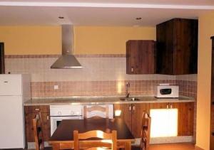 a kitchen with a table and chairs and a microwave at Apartamentos en sierra de gata la Noguera 2 in Villamiel
