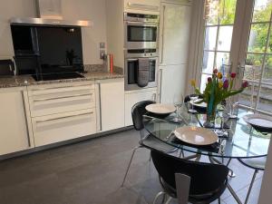 a kitchen with a glass table with chairs and appliances at Fuchsia Cottage in Flushing
