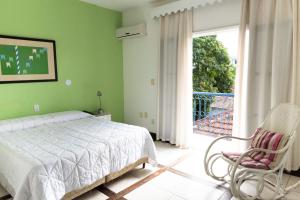 sypialnia z łóżkiem i krzesłem oraz balkon w obiekcie Mara Palace Hotel w mieście Vassouras
