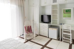 Habitación blanca con escritorio y TV. en Mara Palace Hotel, en Vassouras