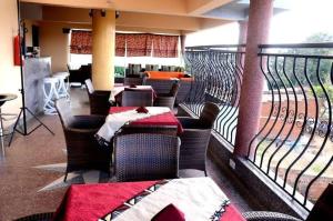 a restaurant with tables and chairs and a balcony at Mujjo Hotel Kajjansi in Kampala
