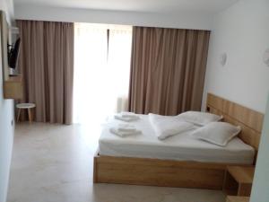 - une chambre avec un lit doté de draps et d'oreillers blancs dans l'établissement Pensiunea Duet, à Sărata-Monteoru