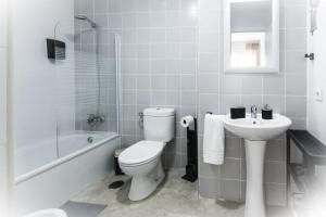 a white bathroom with a toilet and a sink at Apartamento San Juan in El Puerto de Santa María